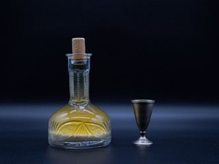 Vintage carafe with homemade vodka and the metal glass on the dark background. Alcoholic drink...