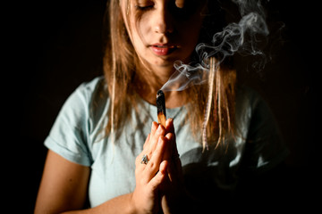 Obraz premium Girl practicing yoga in a studio room hold hands in namaste holding a palo santo