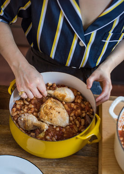 Woman layering Cassoulet ingredients in pot