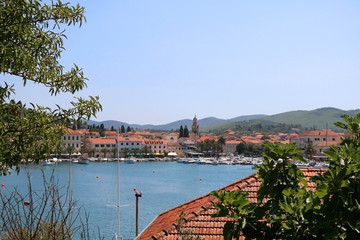 Small picturesque town Vela Luka on island Korcula, Croatia, seen through the trees. Selective focus.