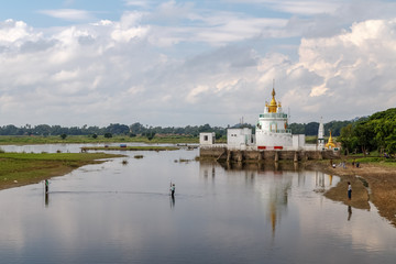 Fototapeta na wymiar View to the Monastery on Taungthaman Lakereflected in the water from U-bein bridge near Amarapura in Myanmar (Burma). Travel Asia. 