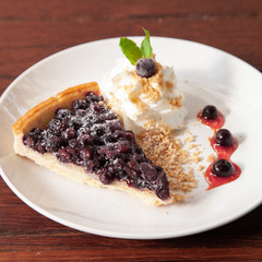Sliced blueberry pie with fresh whipped cream and cookie crumble