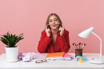 Woman sit at the table holding pencil.