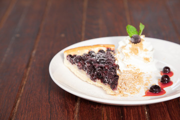 Sliced blueberry pie with fresh whipped cream and cookie crumble