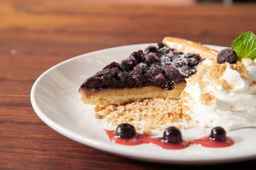Sliced blueberry pie with fresh whipped cream and cookie crumble
