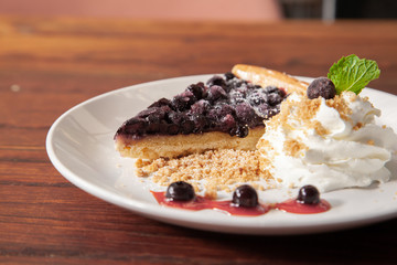 Sliced blueberry pie with fresh whipped cream and cookie crumble
