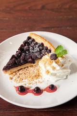 Sliced blueberry pie with fresh whipped cream and cookie crumble