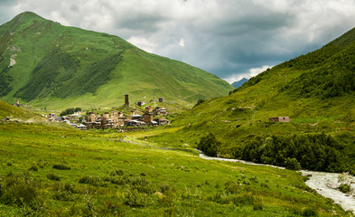 Ushguli village with stormy clouds on the horizon and glacial Patara Enguri river. Svaneti, Georgia.