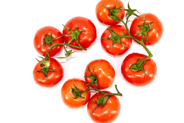 On a white background are red tomatoes fresh and saturated with green branches.