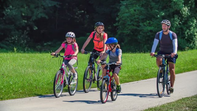 Healthy caucasian family ride bikes together at a park in the morning