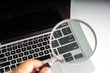 Obraz premium Magnifier and laptop with technology concept.