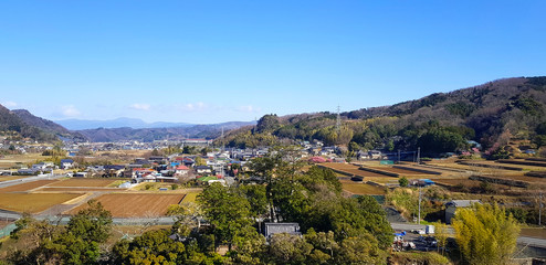 Fototapeta na wymiar Landscape view with city or village, tree, green mountain and clear blue sky at Shizuoka, Japan. Beauty in nature and local area 