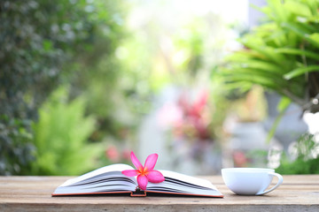 Frangipani flower with White notebook and coffee cup on wooden table
