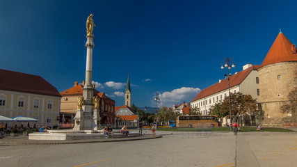 Fototapeta na wymiar Holy Mary monument on square in front of the Cathedral timelapse and Historic buildings in citycentre in Zagreb, Croatia