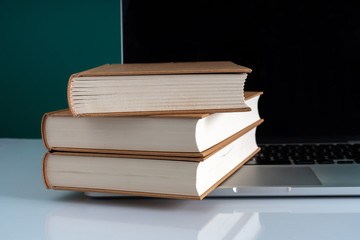 Book stacking on laptop with education concept.