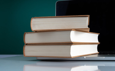 Book stacking on laptop with education concept.