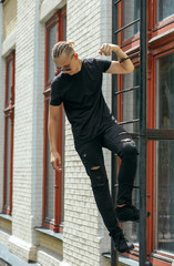 Strong young man hanging on a building stairs
