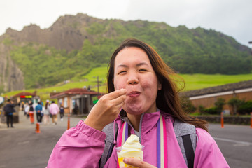 An Asia Chinese lady eat an ice cream, with background of volcanic cone in Jeju-island, Korea