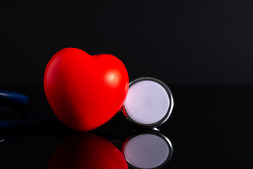 Red heart shape and stethoscope in low light view.