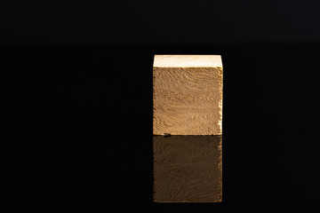 Wooden cube and black background in low light view.