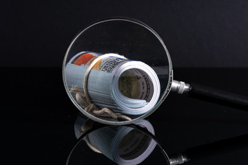 Magnifier and banknotes with low light view. Financial concept.