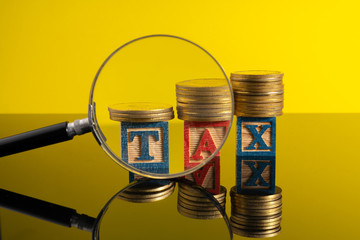 Magnifier glass and stacking coins and tax letter cube with low light view.