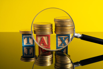 Magnifier glass and stacking coins and tax letter cube with low light view.