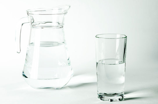 Pure clear water in a glass and jug stands on a white background