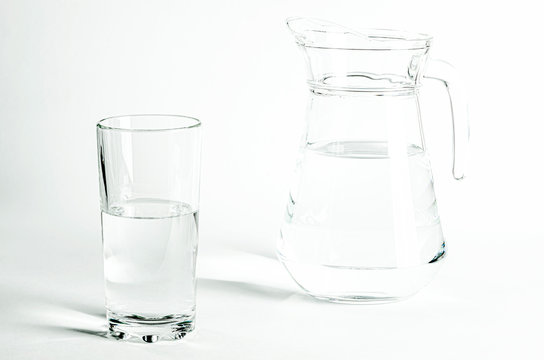 Pure clear water in a glass and jug stands on a white background