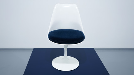 A soft seat vintage chair (armchair) dark-blue and white color. White background, grey floor,  blue podium