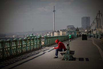 man texting and street drinking on brighton promenade