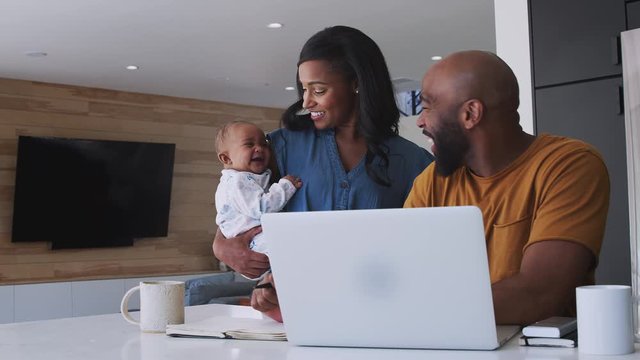 African American Family With Baby Daughter Using Laptop To Check Finances At Home