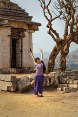 Tourist girl near an ancient building with a tree. The Group of Monuments at Hampi was the centre of the Hindu Vijayanagara Empire in Karnataka state in India