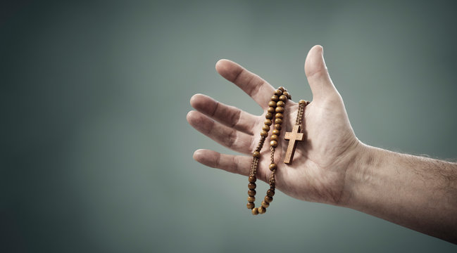 Rosary beads and crucifix cross in hand background