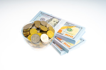 Dollar banknote and glass cup full with coins.