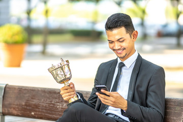Businessman staff seat while holding trophy with successfull concept