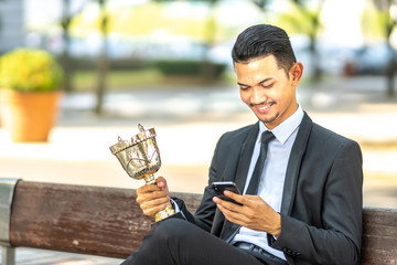 Businessman staff seat while holding trophy with successfull concept