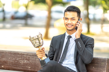 Businessman staff seat while holding trophy with successfull concept