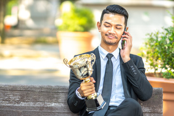 Businessman staff seat while holding trophy with successfull concept