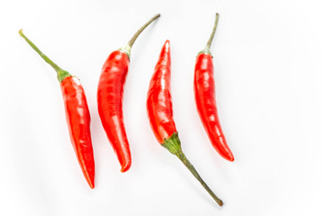 Four fresh red peppers are isolated on white background.
