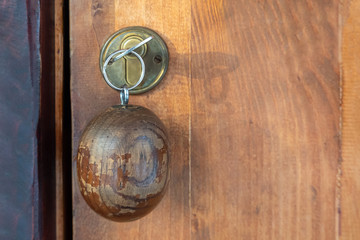 A key with a wooden round keychain inserted into the lock.Selective focus.Close up of key on brown door.Security concept, scenery, entrance to the room