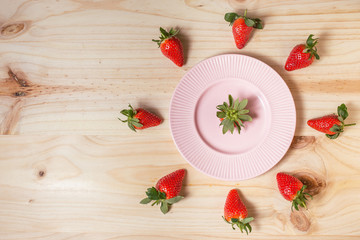 Strawberries in a pink plate on wooden table