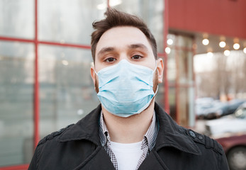 European coronavirus. Portrait of caucasian man wearing facial hygienic mask, respiratory protection mask outdoors. Virus, coronavirus protection, air pollution, ecology, environmental awareness.