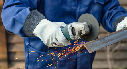 The master cuts metal with a disk grinder