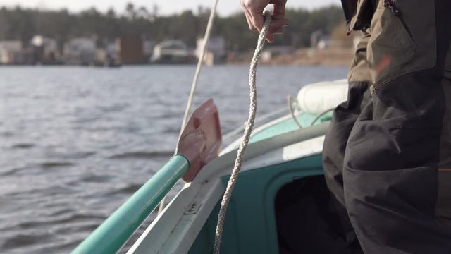 The fisherman lowers the anchor into the water. The concept of fishing from a boat.