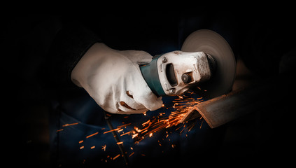 The master cuts metal with a disk grinder