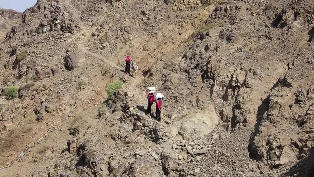 Women bring their food and drink needs through rugged mountain roads because of Al-Houthi militia siege of the villages of Jabal Habashi District in the west of Taiz City