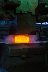 close-up picture of hot steel manual forging process with big mechanical hammer machine