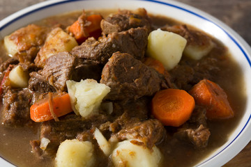 Irish beef stew with carrots and potatoes on wooden table close up