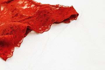 Red lace underwear close-up for background with copyspace. Patterned erotic lingerie, beautiful textiles. Selective focus.